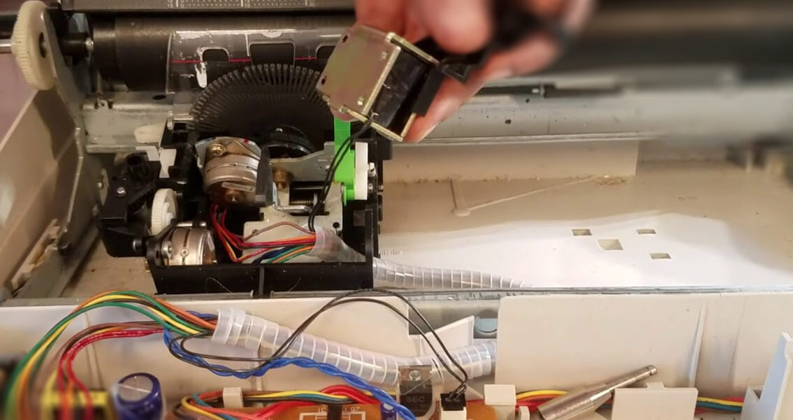 Inside of a Smith Corona typewriter with the print mechanism exposed, showing the pinwheel, solenoid, motor, and colored wiring.